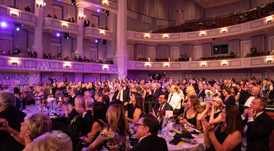 A room full of people dressed in formal wear in a large concert hall.