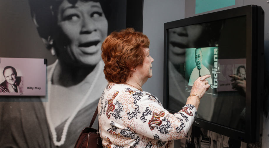 Older woman interacting with an interactive touchscreen to listen to Indiana musicians.