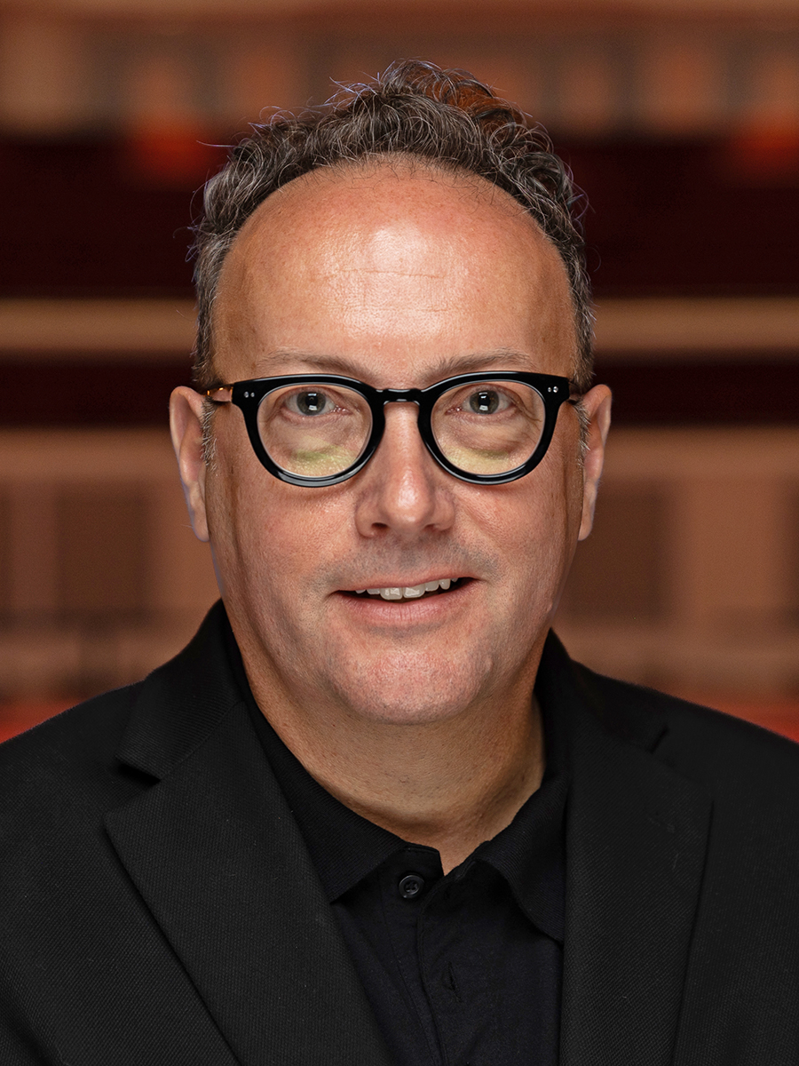 Headshot of a man with glasses and a black suit